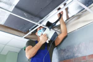 male technician cleaning air duct