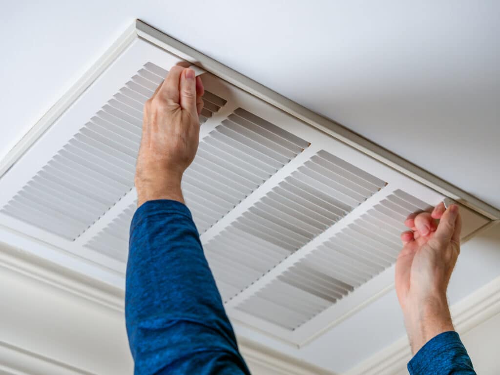 man opening ceiling air vent
