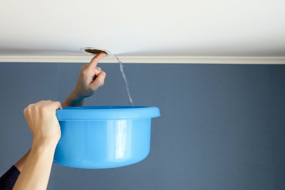 man holding bucket under ceiling water leak
