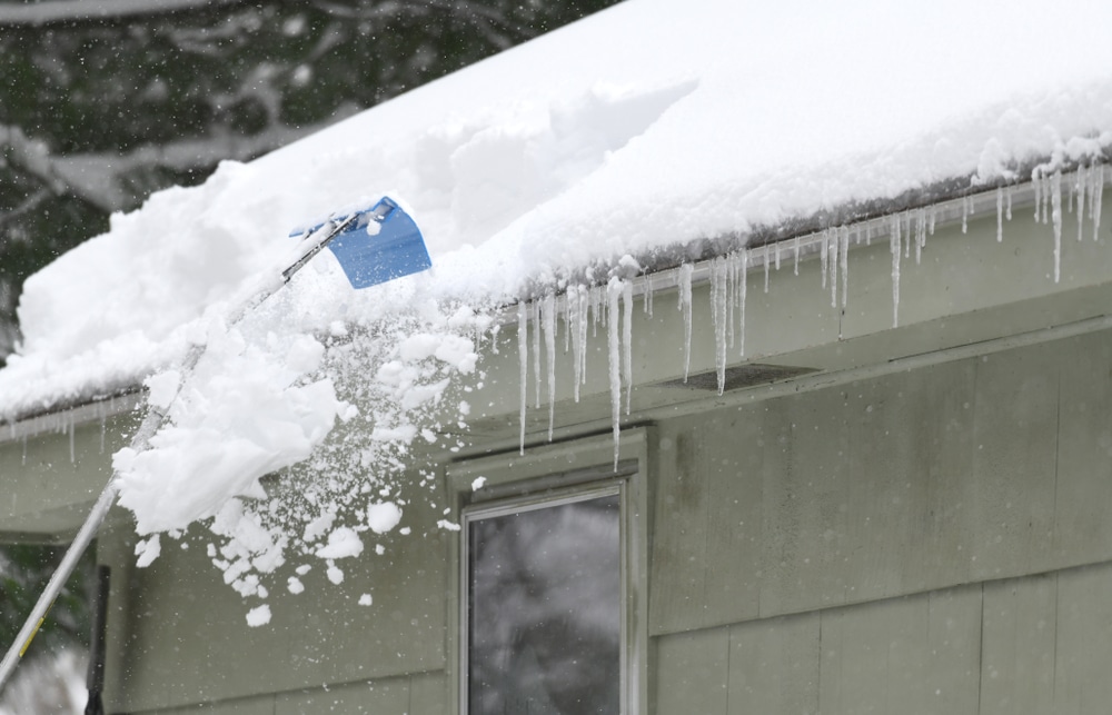 Removing snow on a roof with a roof rake